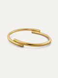 A polished gold open cuff bangle bracelet with a clasp and with engraved Chinese character 心, displayed on a clean off-white background.