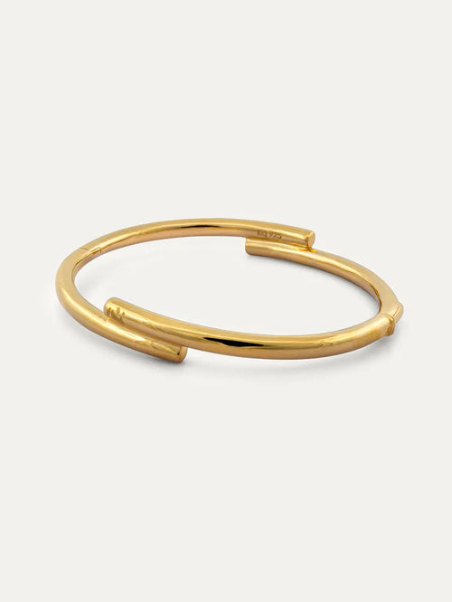 A polished gold open cuff bangle bracelet with a clasp and with engraved Chinese character 心, displayed on a clean off-white background.