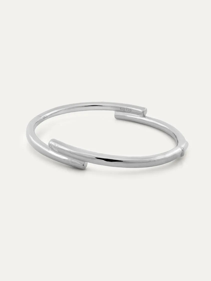 A polished silver open cuff bracelet with a modern design and with engraved Chinese character 心, displayed on a clean off-white background.