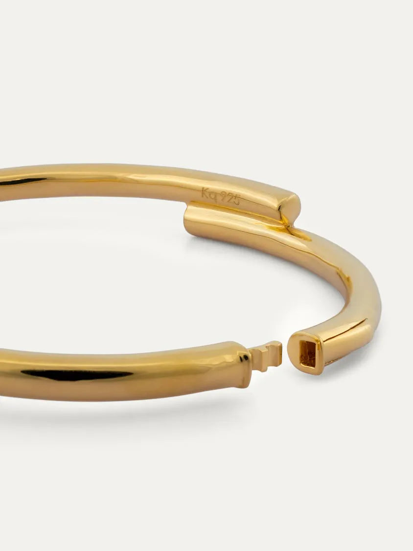A polished 18k gold vermeil open cuff bracelet with a modern design, displayed on a clean off-white background.
