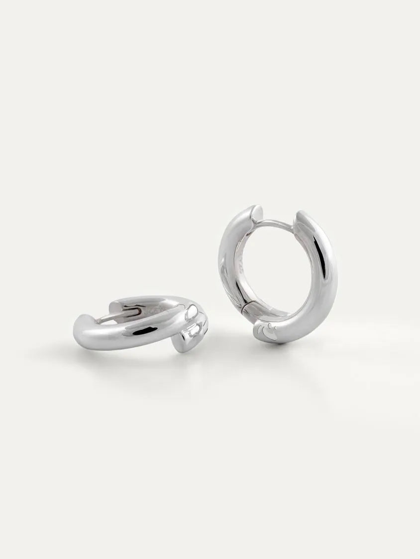 A pair of polished silver hoop earrings on a clean, light off-white background.