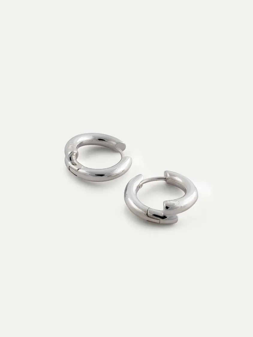 A pair of polished sterling silver hoop earrings on a light off-white background.