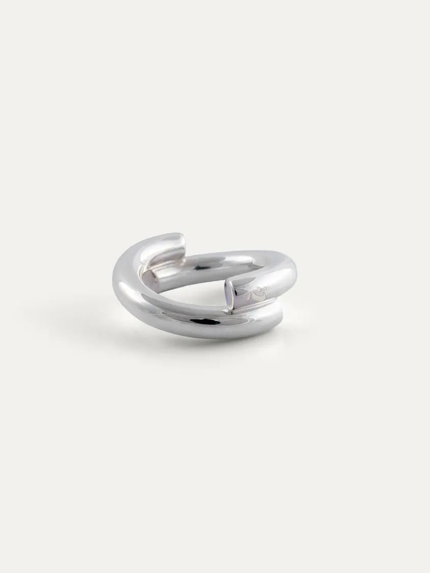A polished sterling silver ring with a modern, open, double-loop design, photographed on a clean, light off-white background.