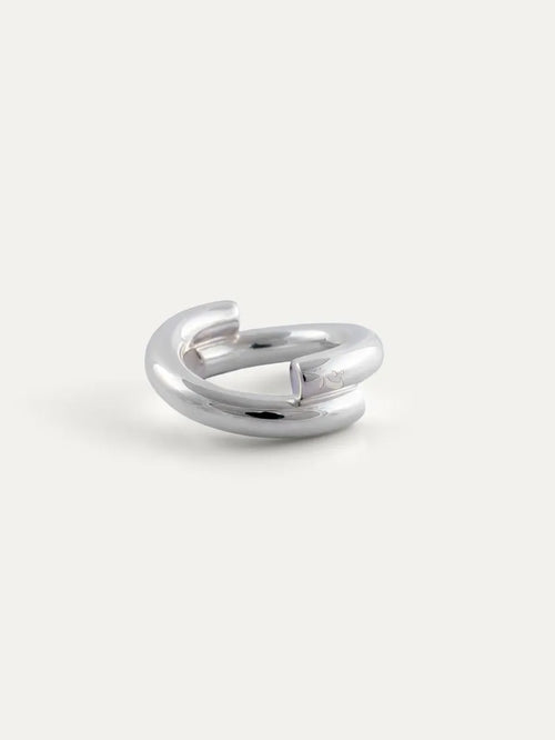 A polished sterling silver ring with a modern, open, double-loop design, photographed on a clean, light off-white background.