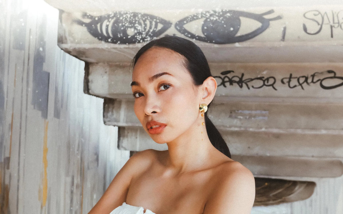 Model under a concrete staircase wearing the Mei Earrings in 18k gold vermeil